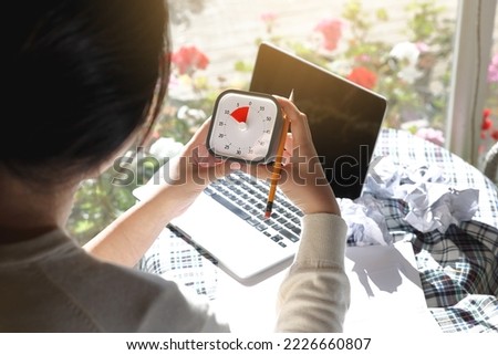 A woman with an impending deadline is holding a timer and looking at it