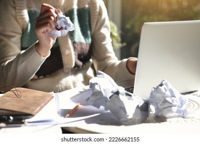 A woman with an impending deadline is throwing crumpled paper in anger - Shutterstock ID 2226662155