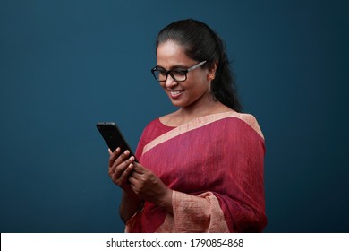 Woman of Indian ethnicity looking at mobile phone with a smiling face expression