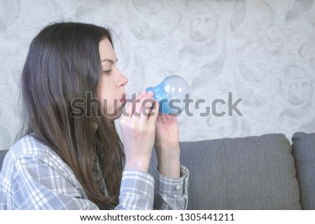 Woman inflates a big bubble from a blue slime. Play with slime.