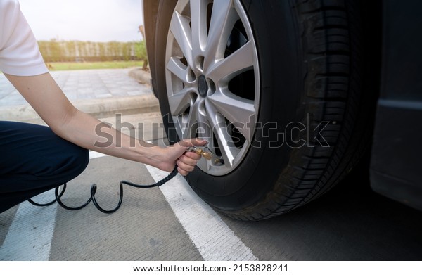 Woman inflates the tire. Woman checking tire pressure\
and pumping air into the tire of car wheel. Car maintenance service\
for safety before travel. Tire inflating point. Filling air in the\
tyre of car