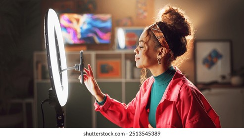 Woman, influencer and phone with ring light for video recording, vlogging or online tutorial at home. Young, female person or vlogger setting up mobile smartphone for advice, tips or content creation - Powered by Shutterstock