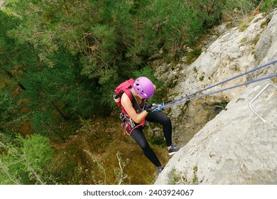 Woman initiating rappel with a forest background
