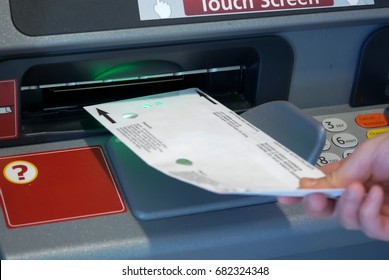 Woman Inserting Envelop To Deposit Money At Bank