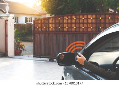 Woman inside car, hand pressing remote control to open the electric auto  door while leaving home.Home remote control, auto garage, security system in concept. Dark tone.
