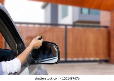 Woman inside car, hand using remote control to open the auto gate when driving and arrive home. Security system and wireless concept.