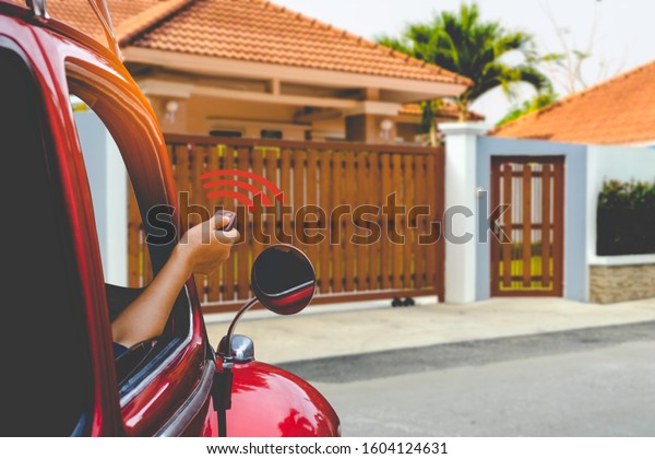 Woman inside red car, hand\
pressing remote control to open or close the electric sliding auto\
wood door.Home remote control, auto garage, security system in\
concept. 