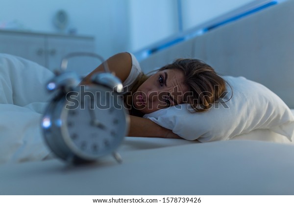Woman with insomnia lying in bed with open eyes.\
Girl in bed suffering insomnia and sleep disorder thinking about\
his problem at night