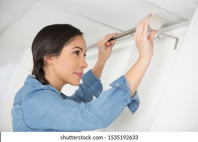 Woman Installing Some New Curtains At Home