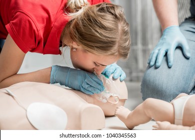 Woman instructor showing how to make artificial respiration with dummy during the first aid training indoors