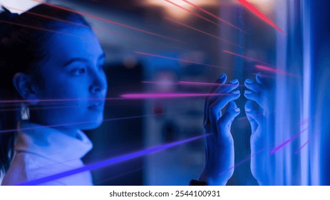 A woman interacts with a futuristic digital interface, bathed in blue and pink light. Neon blue concept of technology, innovation, and digital interaction. Futuristic technology image. - Powered by Shutterstock