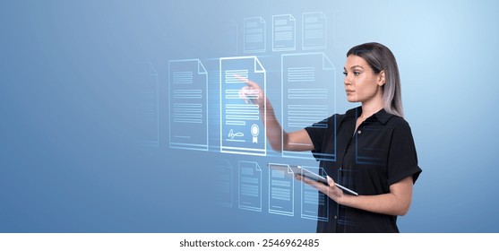 A woman interacts with virtual holographic documents, navigating them with her hand and tablet. Blue digital background. Concept of digital document management - Powered by Shutterstock