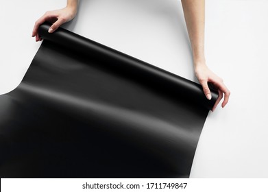 Woman Interior Designer Holding In Hands Scroll Paper Roll. Roll Of Black Wallpaper On White Background. Copy Space For Text