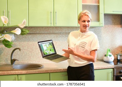 Woman Interior Designer In The Kitchen Shows The Project On The Laptop. Meeting With The Customer At Home. Buying A Kitchen