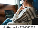Woman investing in world stock market, using her laptop and online trading soft from home