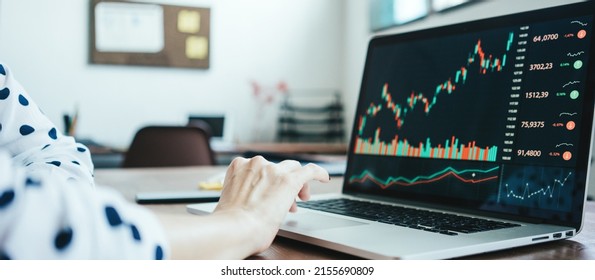 Woman investor working with laptop at loft workplace. Stock exchange charts on the screen. Hands close-up - Powered by Shutterstock