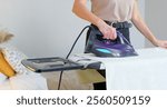 Woman Ironing Clothes at Home on Ironing Board. High quality photo