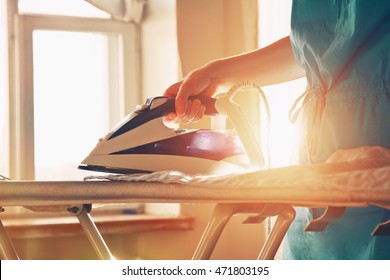 woman ironing clothes on ironing board