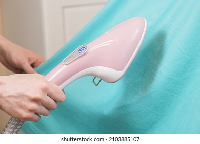 Woman Ironing Green Shirt Handheld Garment Steamer. Vertical Steam Irons Brushes For Ironing Clothes Generator. Household Garment Steamer Handheld Ironing Machine