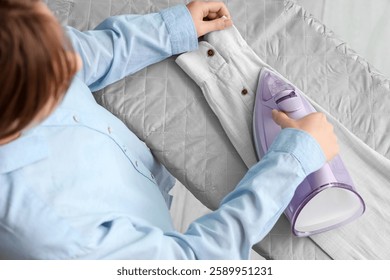 Mujer que plancha la manga de la camisa a bordo en casa, vista superior
