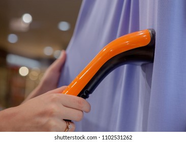 Woman Ironing Violet Dress With A Small Steam Ironing Machine.