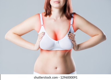 Woman with irritated skin under bra, irritation on the body from underwear on gray background, painful area highlighted in red