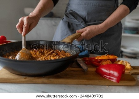 Woman ist stirring a pan with ready cooked meal