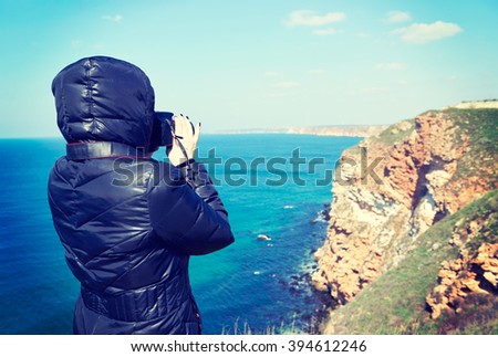 A woman in a jacket, traveler, on a background of the nature sea landscape of Bulgaria Cape Kaliakra makes photo