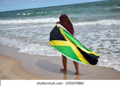 Woman With Jamaican Flag Walking Along Beach