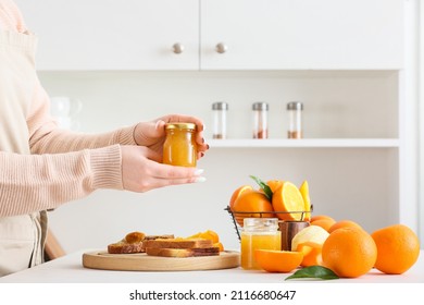 Woman With Jar Of Tasty Orange Jam In Kitchen