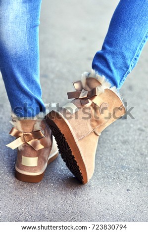 Woman in jeans wearing warm, fuzzy sheepskin boots ,walking on the street 