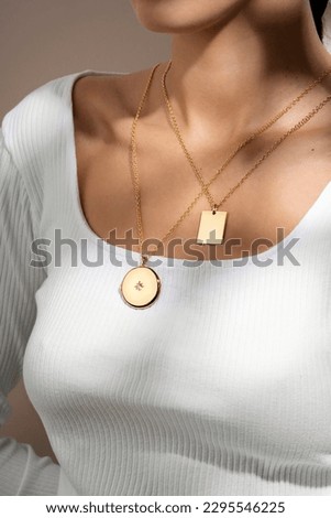 Woman Jewelery concept. Beautiful model brunette in modern gold metal necklace chain. Beige background