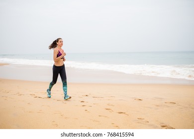 Woman is jogging along the seashore on an overcast day - Powered by Shutterstock