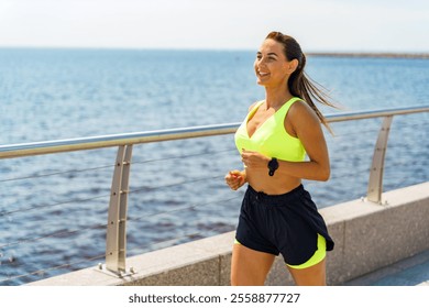 Woman jogging along the waterfront promenade on a sunny day, enjoying her exercise routine - Powered by Shutterstock