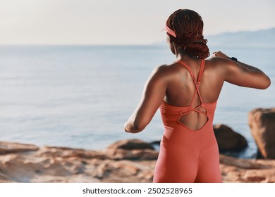 Woman jogging by the serene ocean at sunrise in a stylish athletic outfit - Powered by Shutterstock