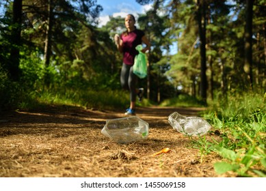 Woman jogging with garbage bag in forest. Collecting trash. Plogging concept - Shutterstock ID 1455069158