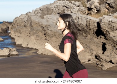 woman jogging on a rocky beach. Outdoor fitness and exercise concept. Design for poster, banner, and postcard. Side view - Powered by Shutterstock