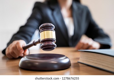Woman judge hand holding gavel to bang on sounding block in the court room. - Shutterstock ID 1278676255
