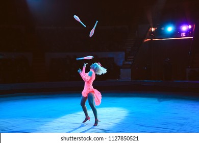 A woman juggles in the circus arena.
