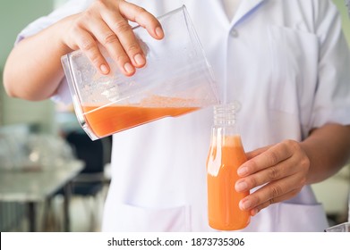 Woman juicing cold pressed juice and pouring into bottle.Wellness food or detox smoothie.Vegetable and fruit juice healthy with food juicer machine.