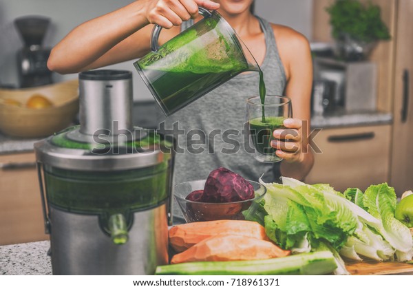 Woman juicing\
making green juice with juice machine in home kitchen. Healthy\
detox vegan diet with vegetable cold pressed extractor to extract\
nutrients for smoothie\
drink.