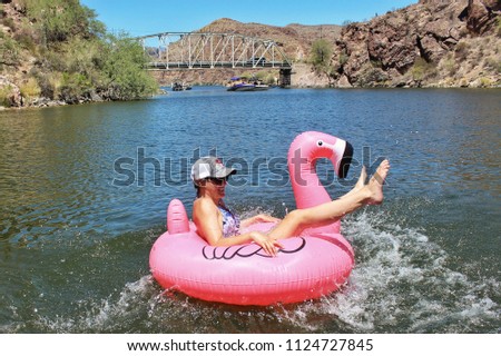 Woman jump jumping into a pink flamingo floatie