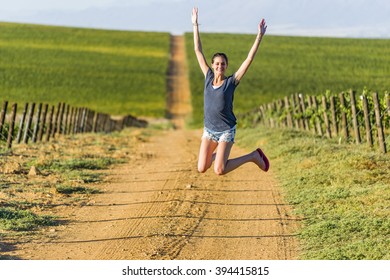 Woman Jumping In Grape Winelands Wineyard At Sunset