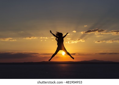 Woman jumping for joy and happines on sunset