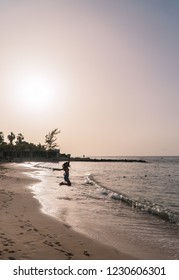 Woman Jumping For Joy While On Holiday At The Beach In Jamaica, Caribbean. Vintage Filter