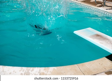 Woman Jumping Off Diving Board Doing A Cannon Ball Lands With Big Splash In The Swimming Pool. Girl Underwater, Jumps Off Diving Board Into An Outdoor Swimming Pool.