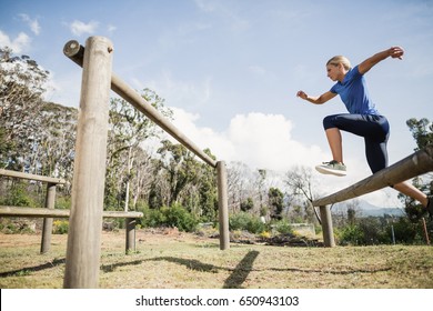 Woman jumping over the hurdles during obstacle course in boot camp
