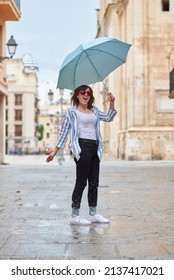 Woman Jumping Over A Puddle On A Rainy Day