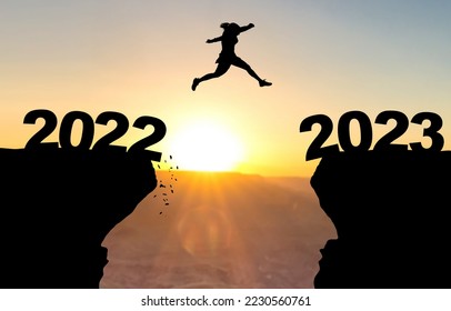 Woman jumps over abyss with sunset in background and inscription 2022 and 2023 - Shutterstock ID 2230560761