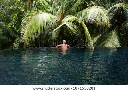 Rückansicht einer blonden Frau  im Infinity Pool